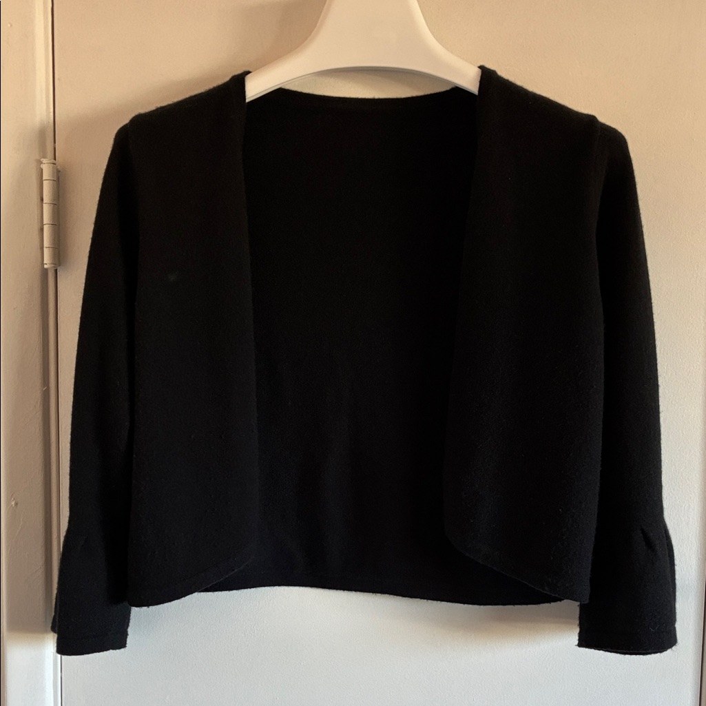 A resale listing photograph of a knitted shrug, priced in US dollars in September 2026